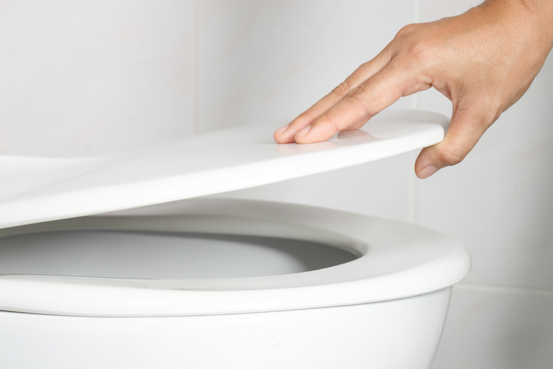 Man's Hand Opening the Toilet Lid